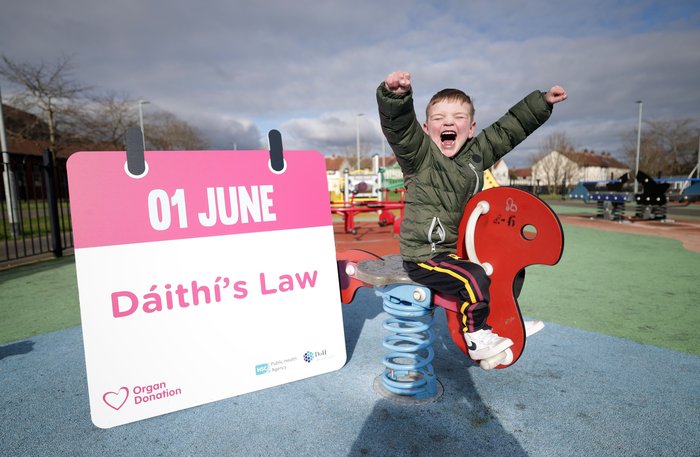 Boy in a playpark cheering next to Daithi's Law sign