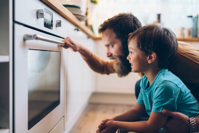 Father and son looking into oven