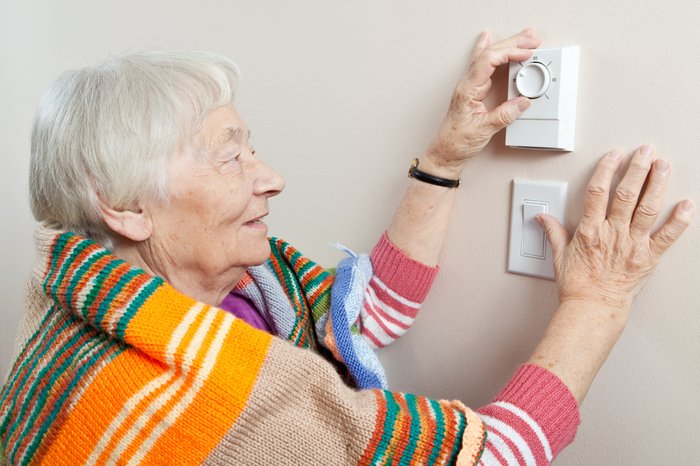 Old woman adjusting thermostat